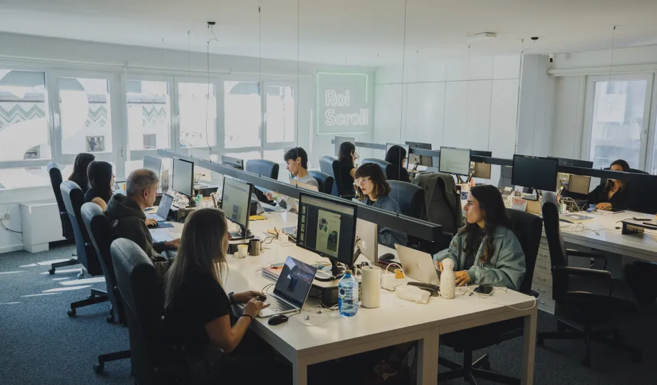 Personas trabajando frente a varios monitores en una oficina.