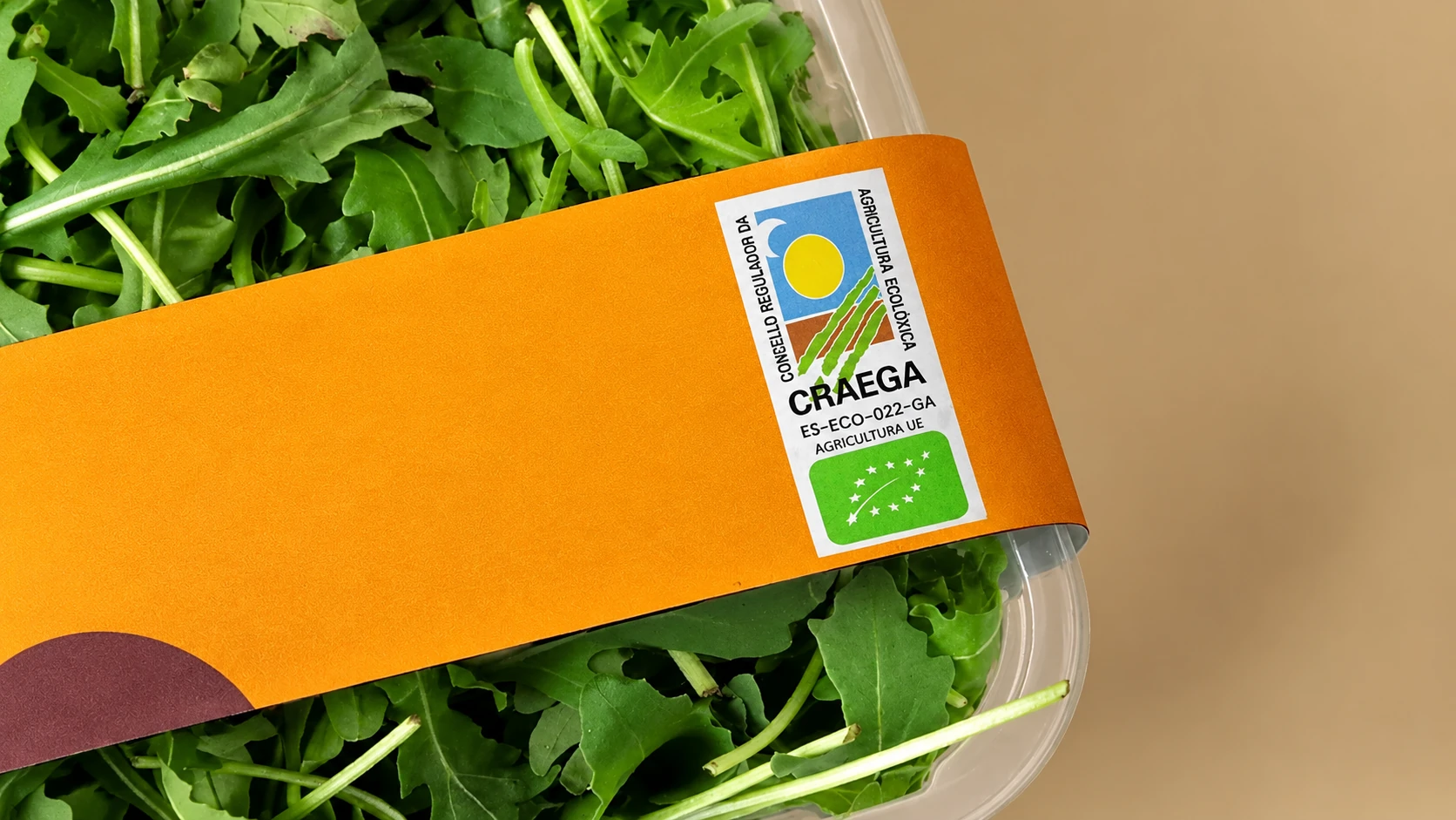 Envase naranja con el sello CRAEGA entre hojas verdes.